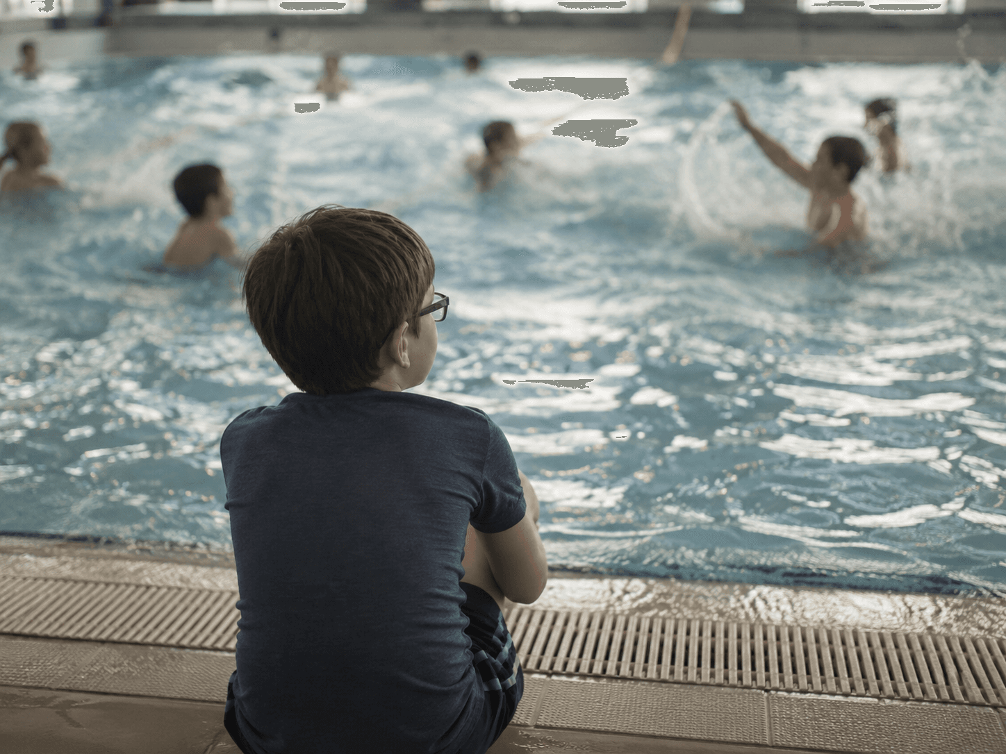 Copil pe marginea piscinei privind alți copii înotând